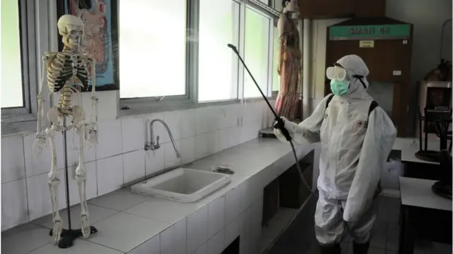 Petugas Palang Merah Indonesia menyemprotkan cairan disinfektan di sebuah SMP di Jakarta, Senin (16/03).