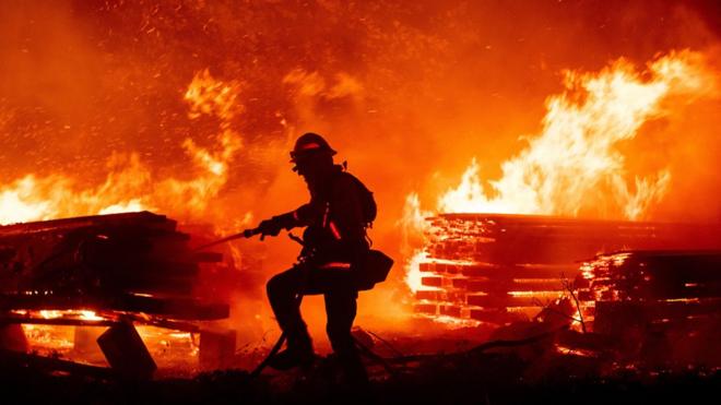 A firefighter douses flames as they push towards homes during the Creek fire in the Cascadel Woods area of unincorporated Madera County, California on 7 September 2020
