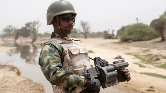 Nigerian soldier wey carry grenade launcher tanda for di Yobe river wey separate Nigeria from Niger Republic, Damasak town for North East, as thousands of people wey dem free from Boko Haram dey go back to dia house.