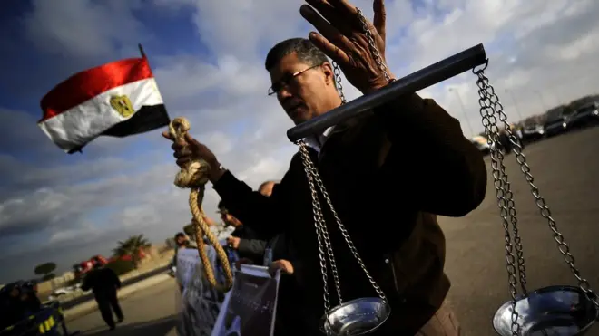Un homme exhibe une corde d'exécution et une balance de la justice, lors du procès du président Hosni Moubarak en 2011.