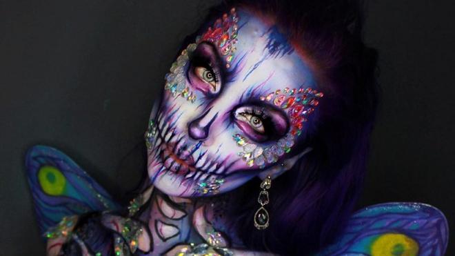 Ellie transforms herself into a fairy of death merging the aspects of a violet and pink skull and a pale blue butterfly