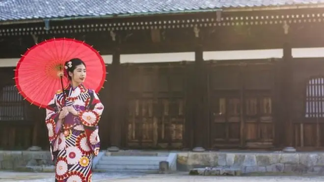 A woman stands in traditional clothing outside a Japanese temple