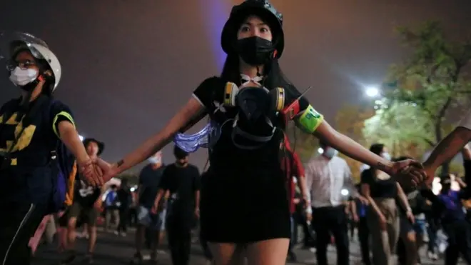 A group of protesters hold hands as they march through Bangkok