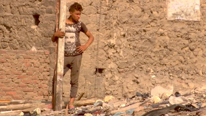 أحد السكان مستندا على قائم من الخشب وسط الركام