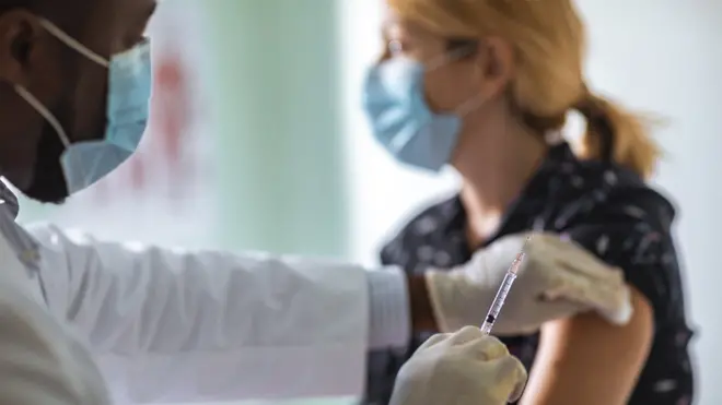 Doctor administering injection to young woman