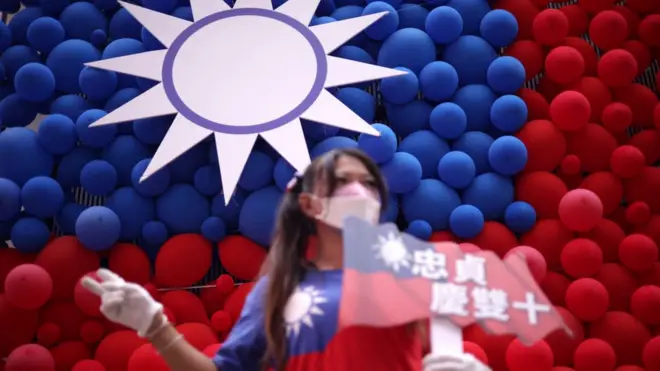 A woman poses for photos in front of a Taiwanese flag made with balloons during a fair to mark the National Day at Zhongzhen New Village Cultural Park on October 10, 2023