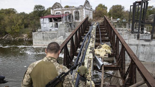 Ukrainian soldiers cross damaged bridge at Velyka Oleksandrivka town, recaptured by Ukrainian forces, on 24 October