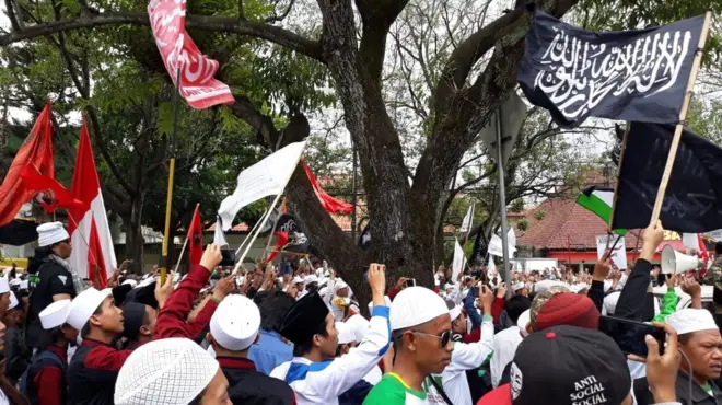 Massa FPI mengibarkan berbagai bendera di luar gedung pengadilan.