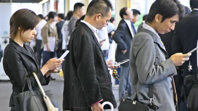 أشخاص منهمكون في قراءة رسائلهم الإلكترونية أثناء توجههم للعمل