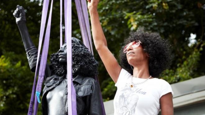 Jen Reid poses next to a sculpture by Marc Quinn portraying her, titled "A Surge of Power (Jen Reid) 2020", in Bristol,