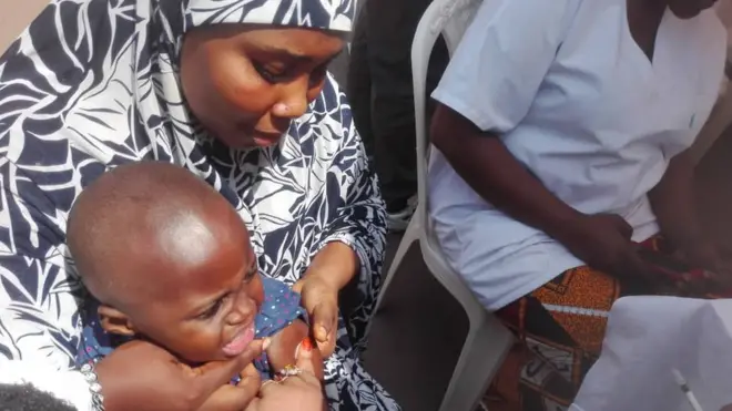 Woman hold her pikin wey dey collect vaccine
