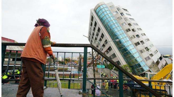 A local resident looks out at a building leaning at a precarious angle in Hualien on February 8, 2018 after the city was hit by a 6.4-magnitude quake late on February 6.