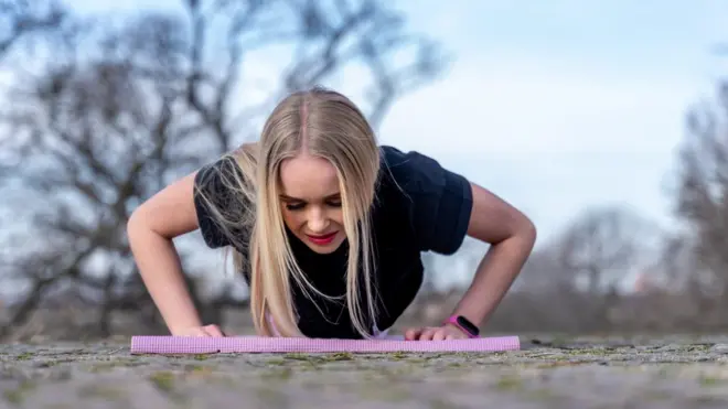 Una mujer hace flexionesbloco vaidebetpecho al aire libre