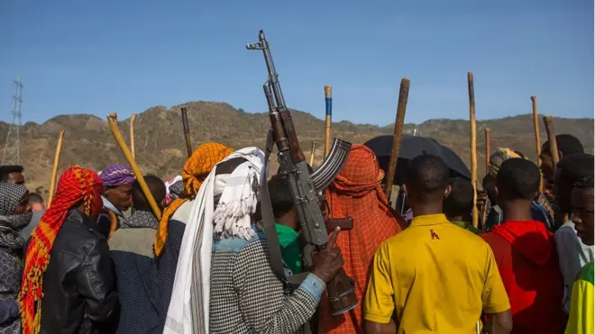 ሰዎች የጦርመሣሪያ እና ዱላ ይዘው ሲጨፍሩ