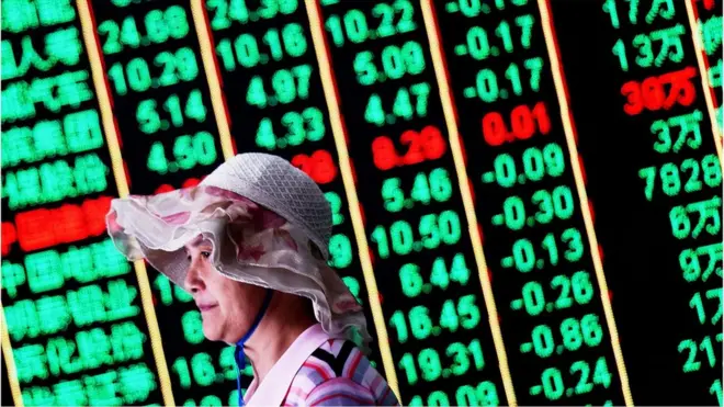 一名妇女走过中国股市展示牌