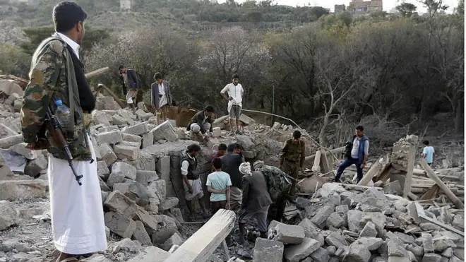 Warga sipil di antara reruntuhan rumah warga sipil di Sanaa, Yaman, sesaat setelah serangan udara pasukan koalisi pimpinan Arab Saudi.