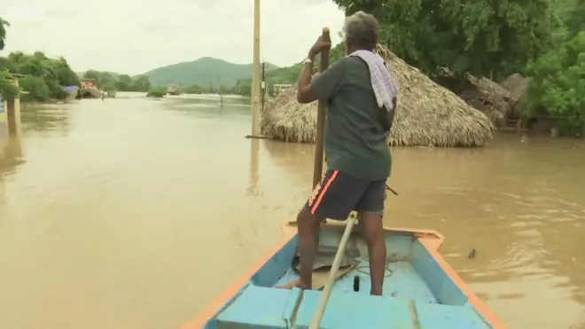 వరద నీటిలో పడవపై వ్యక్తి