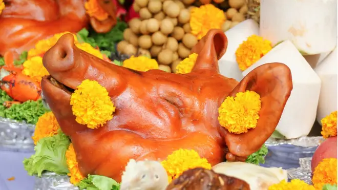 Голова свиньи, украшенная желтыми хризантемами