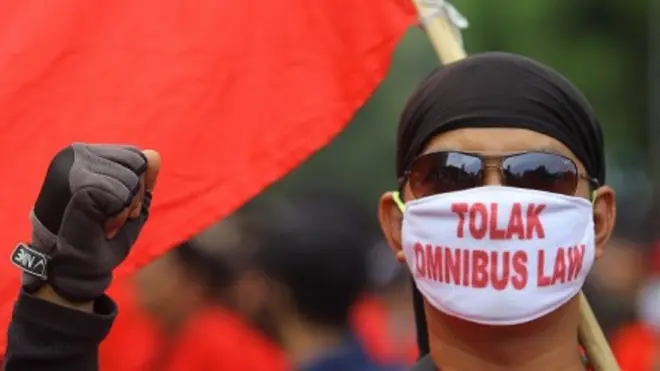 Seorang pengunjuk rasa yang tergabung dalam Gerakan Tolak Omnibus Law (GETOL) memakai masker bertuliskan Tolak Omnibus Law saat berunjuk rasa menuju Gedung Negara Grahadi di Surabaya, Jawa Timur, Selasa (20/10/2020).