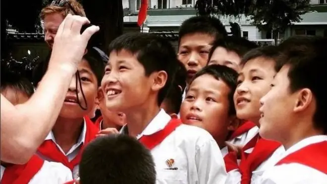 Anak-anak sekolah Korea Utara melihat foto mereka yang diperlihatkan seorang turis.
