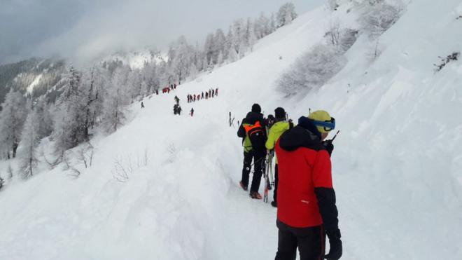 Группа спасателей в ярких куртках на заснеженном склоне горы