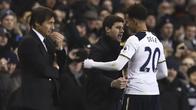 Manajer Spurs, Maurico Pochettino, berbincang dengan Dele Alli yang memborong dua gol ke gawang Chelsea. Sementara manajer Chelsea, Antonio Conte, menatap ke arah lapangan.