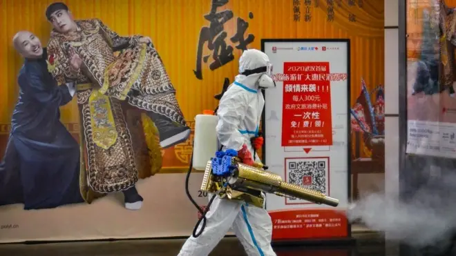 Seorang petugas melakukan penyemprotan disinfektan di salah-satu ruas jalan di kota Wuhan, Minggu (24/01).