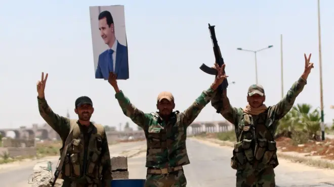 Militares con una foto de Bashar al Asad