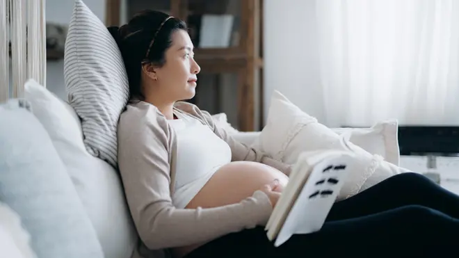 Una mujer asiática embarazada leyendo un libro