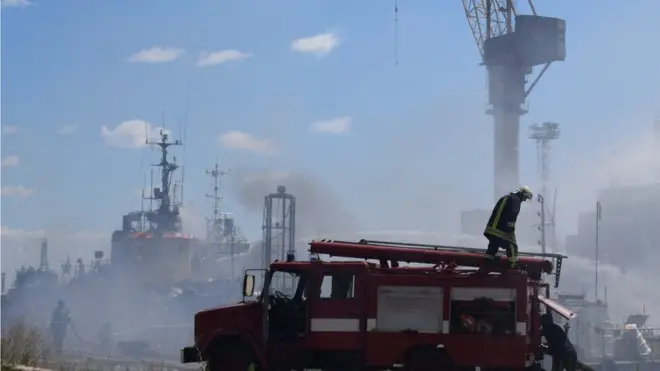 سيارة إسعاف في ميناء أوديسا الذي يتصاعد منه الدخان