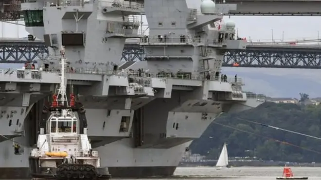 全新的英国皇家海军“伊丽莎白王后号”航空母舰借着低潮下水，并通过沿途的大铁桥。