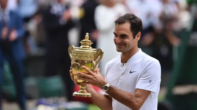Roger Federer memegang trofi juara tenis putra Wimbledon setelah mengalahkan Marin Cilic di final.