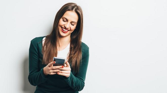 Una mujer escribiendo en un celular