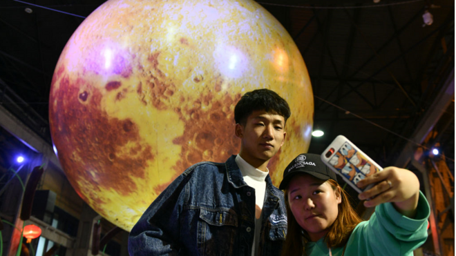 2018年中秋节前夕，中国民众在一个月球状的灯笼前拍照。