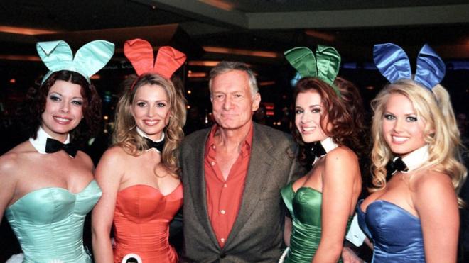 Hugh Hefner with four women in Playboy uniforms