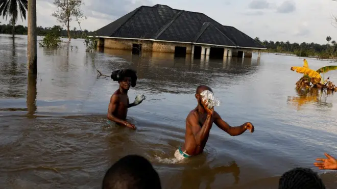 Des habitants pataugent dans les eaux de crue après une inondation massive dans la communauté d'Obagi, dans l'État de Rivers, au Nigéria.