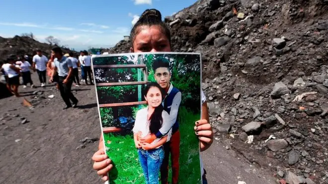 Una mujer sostiene la foto de unos familiares que murieron por la erupción del Volcán de Fuego el 3 de junio de 2018 en el primer aniversario de la tragedia en San Miguel Los Lotes, Guatemala.