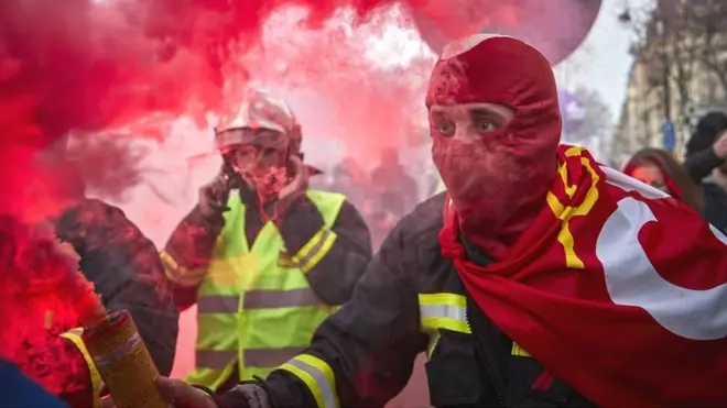 A fireman holds a flare aloft during a protest against pension reform plans in Paris, 10 December 2019