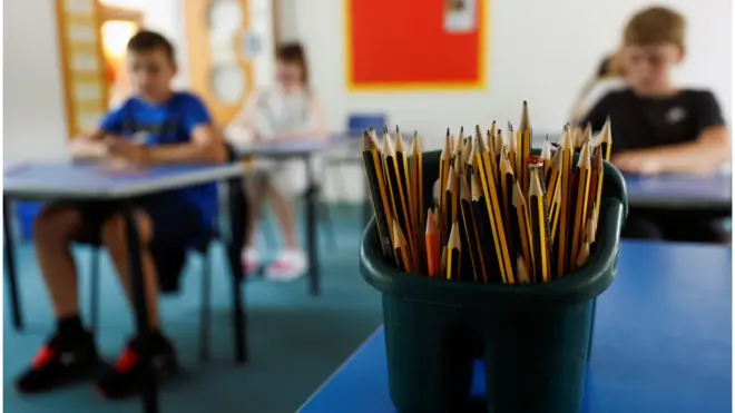 تلاميذ في الفصل الدراسي أثناء تفشي الفيروس، تاركين مسافة بينهم