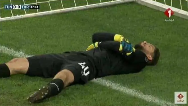 Kiper timnas Tunisia, Mouez Hassen, berbaring di depan gawang saat maghrib tiba.