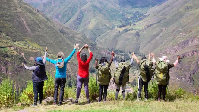 Carregadoras, guias e andarilhasaposta esportiva amanhãbraços dados e observando a vista da Trilha Inca