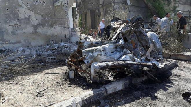 People inspect the site of a car bomb blast in Damascus in this handout picture posted on SANA on July 2, 2017, Syria