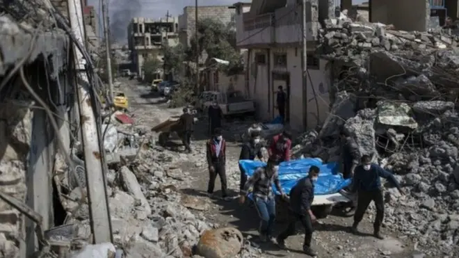 Penduduk membawa mayat ke luar gedung yang runtuh akibat serangan di kota Jadideh.