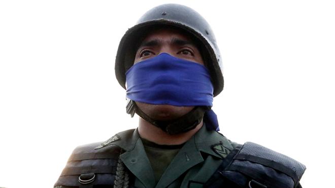 Militar uniformizado e com um lenço azul no rosto