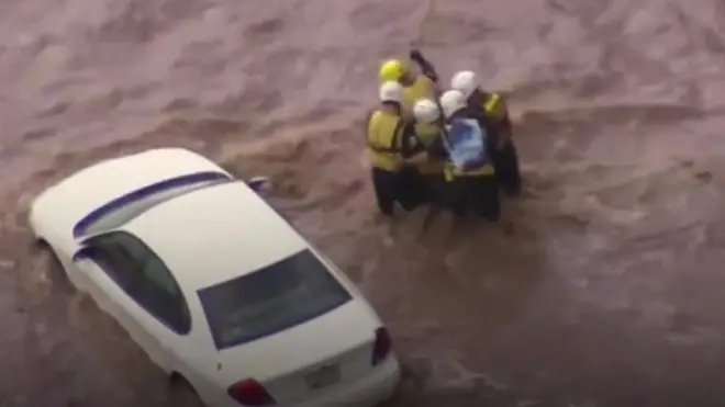 Emergency crews are shown rescuing a driver from his car.