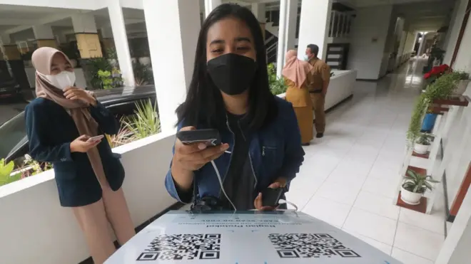 Seorang warga sedang memindai QR Code dengan Aplikasi Pedulilindungi