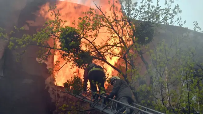 Firefighters try to extinguish a fire in a residential building following bombardment in central Kharkiv on 17 April 2022