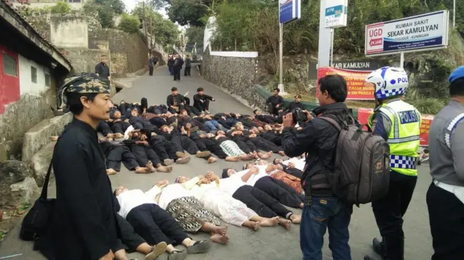 Anggota masyarakat penghayat Sunda Wiwitan merebahkan tubuh mereka di jalan sebagai tanda penolakan eksekusi lahan adat.