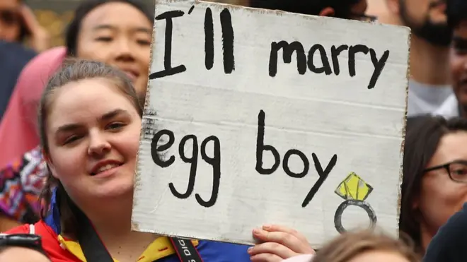Seorang pemrotes dalam aksi menuntut mundurnya Senator Australia, Fraser Anning, dan mengajak bersatu melawan rasisme dan Islamofobia, membawa papan kertas yang bertuliskan "Saya akan menikahi egg boy", merujuk pada pemuda asal Melbourne, Will Connolly, yang melemparkan telur ke Anning.