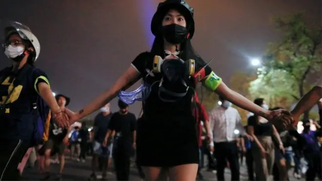 A group of protesters hold hands as they march through Bangkok
